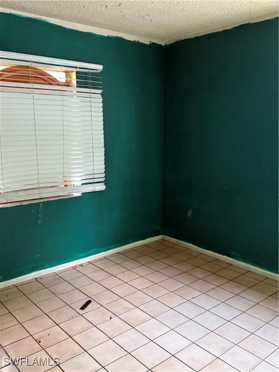 tiled empty room with a textured ceiling