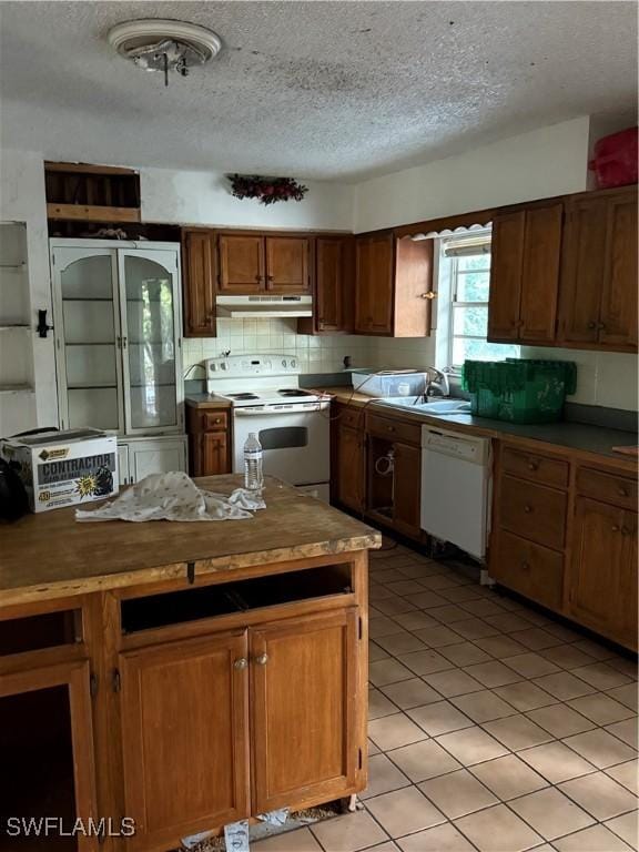 kitchen featuring a textured ceiling, white appliances, sink, light tile patterned floors, and butcher block countertops