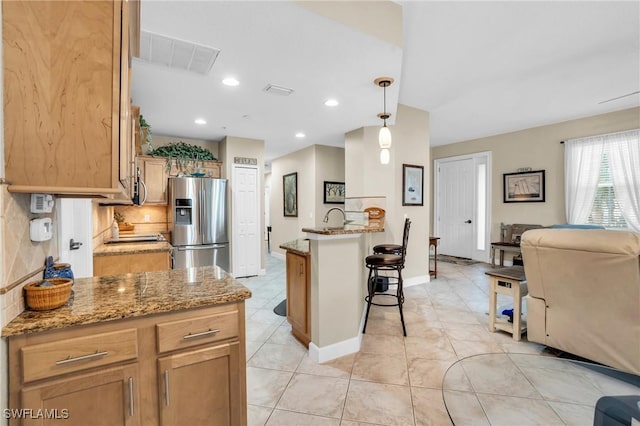 kitchen with light stone countertops, pendant lighting, a kitchen island, and stainless steel appliances