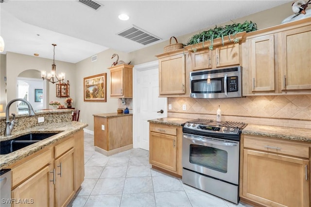 kitchen featuring pendant lighting, sink, decorative backsplash, appliances with stainless steel finishes, and a notable chandelier