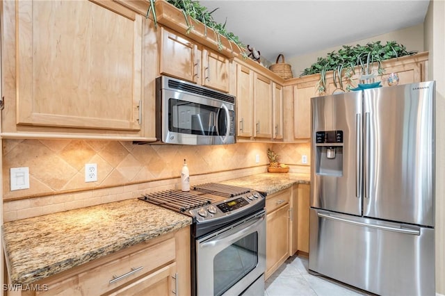 kitchen with appliances with stainless steel finishes, light stone counters, and light brown cabinetry