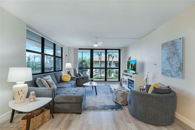 living room with ceiling fan, light hardwood / wood-style flooring, and a wall of windows