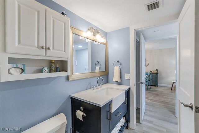 bathroom with toilet, vanity, and hardwood / wood-style flooring