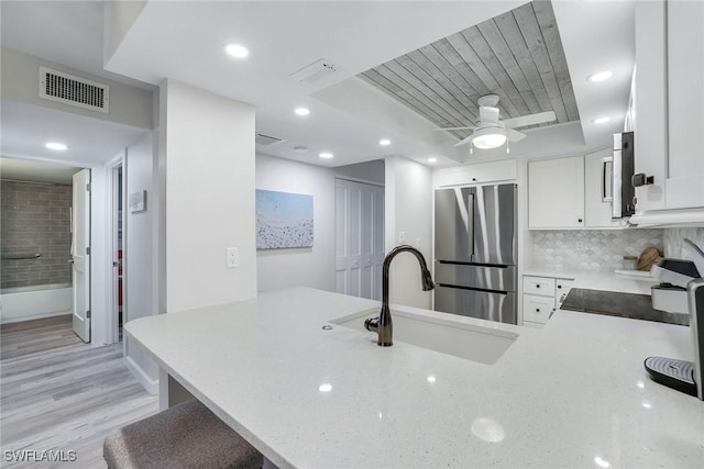 kitchen featuring kitchen peninsula, white cabinets, stainless steel refrigerator, and sink