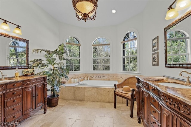 bathroom with tiled tub, a wealth of natural light, and vanity