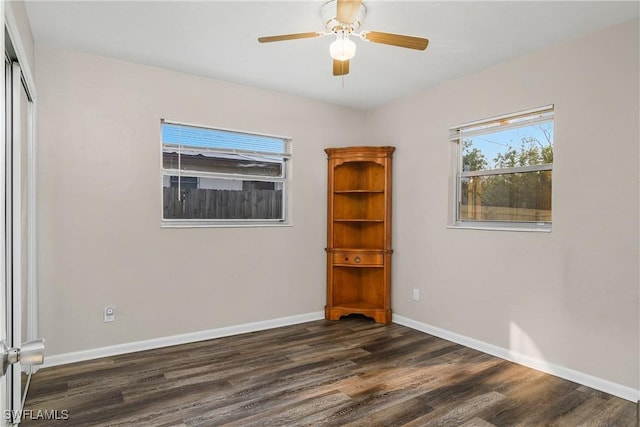 unfurnished room featuring ceiling fan, dark wood-type flooring, and a wealth of natural light