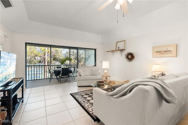 living room featuring ceiling fan, light tile patterned flooring, and a tray ceiling