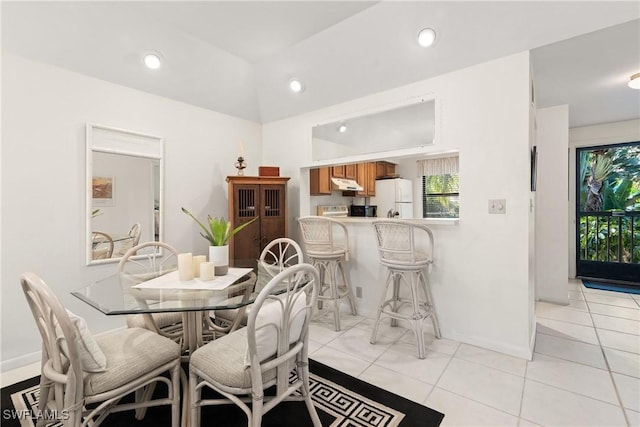 dining room featuring vaulted ceiling and light tile patterned flooring