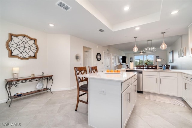 kitchen featuring hanging light fixtures, stainless steel dishwasher, white cabinets, a breakfast bar, and sink