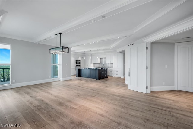 unfurnished living room featuring a chandelier, wood-type flooring, crown molding, and sink