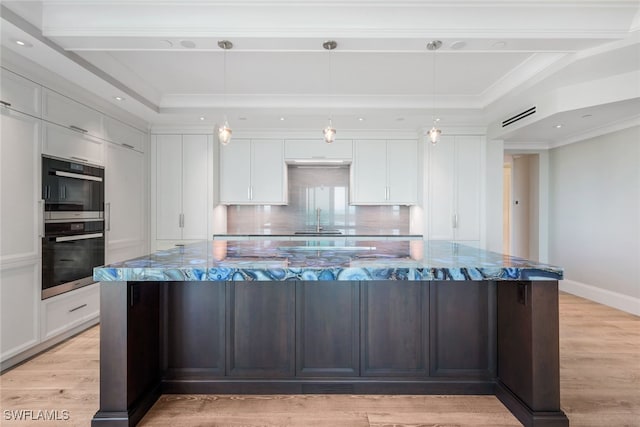 kitchen featuring decorative backsplash, light stone counters, white cabinets, hanging light fixtures, and a large island