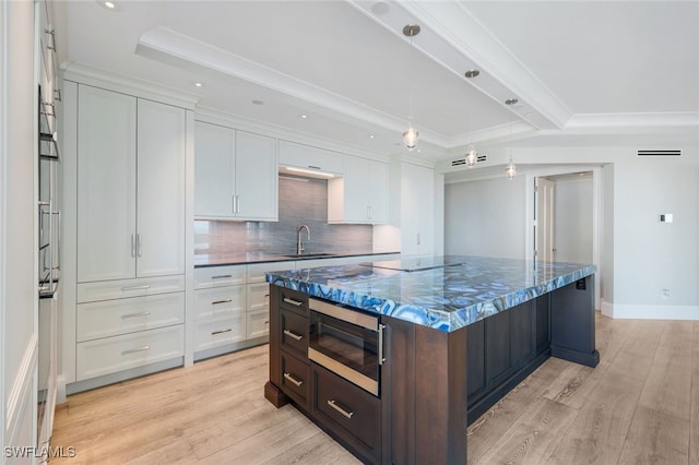 kitchen featuring white cabinets, backsplash, a center island, and sink