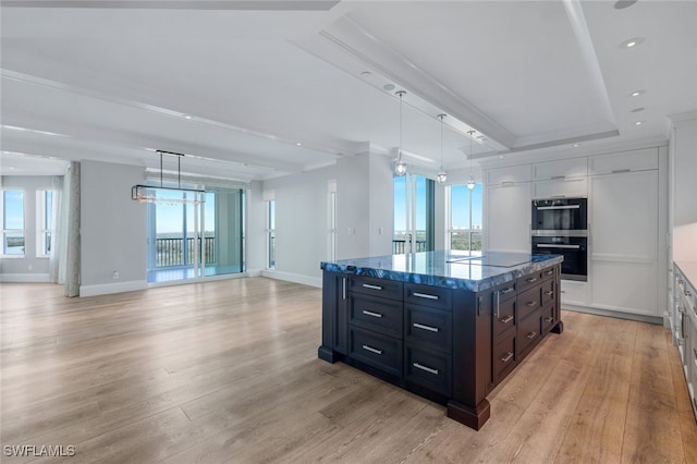 kitchen with a kitchen island, light hardwood / wood-style flooring, pendant lighting, black electric stovetop, and double wall oven