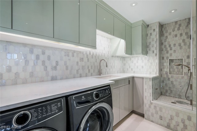 clothes washing area featuring cabinets, washer and clothes dryer, and sink