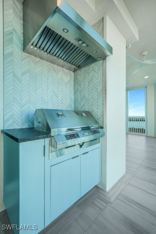 kitchen with wall chimney exhaust hood, white cabinetry, and light tile patterned floors