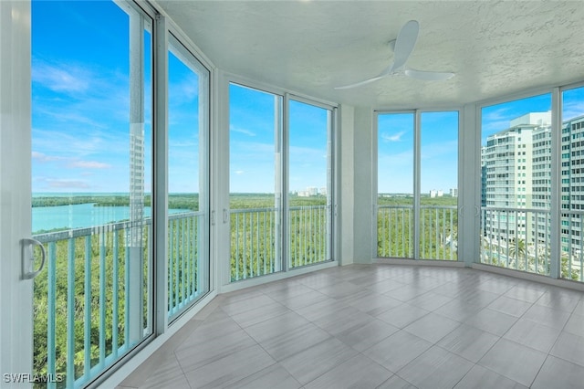 unfurnished sunroom featuring a water view and ceiling fan