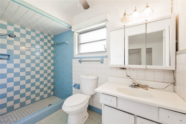 bathroom with vanity, tile patterned flooring, toilet, tile walls, and a tile shower