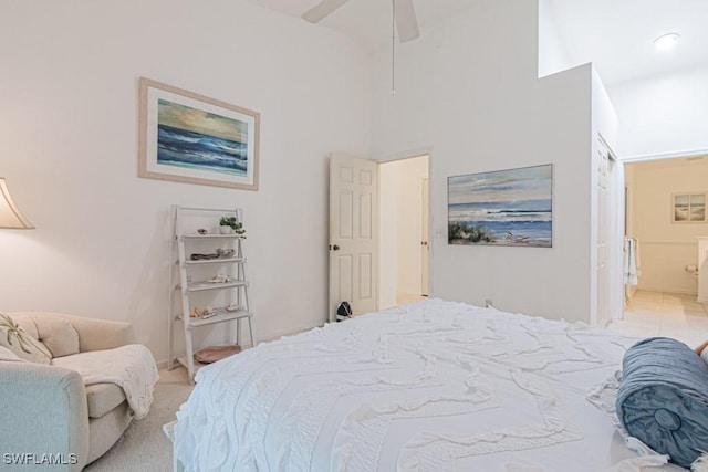 carpeted bedroom featuring ceiling fan and a high ceiling