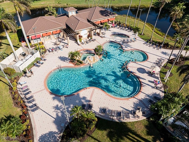 view of swimming pool featuring a hot tub, a water view, and a patio area