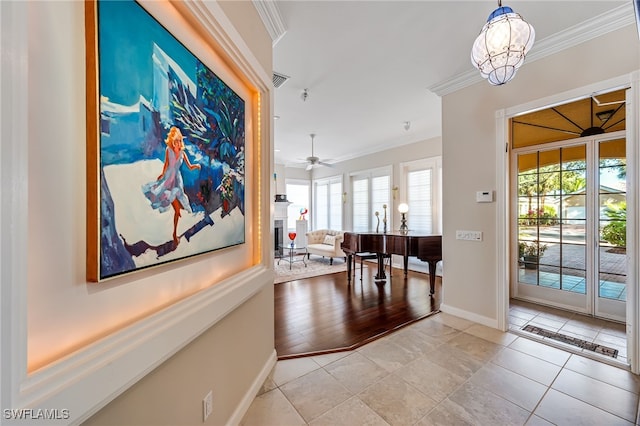 corridor with a wealth of natural light, light tile patterned flooring, and ornamental molding