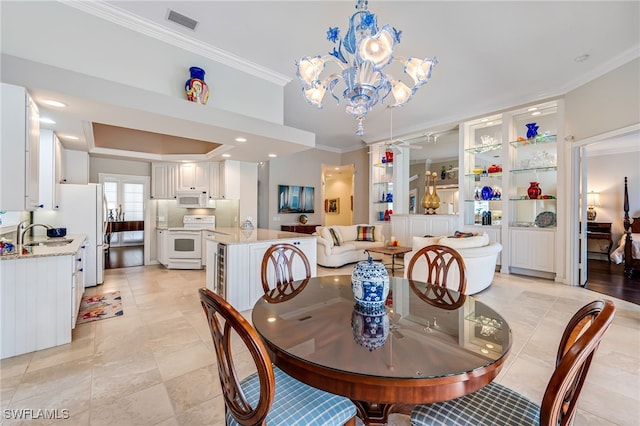 dining room with sink, crown molding, and a chandelier