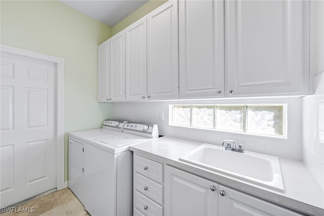 washroom featuring washing machine and clothes dryer, sink, and cabinets