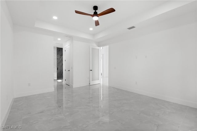 spare room with a raised ceiling and ceiling fan