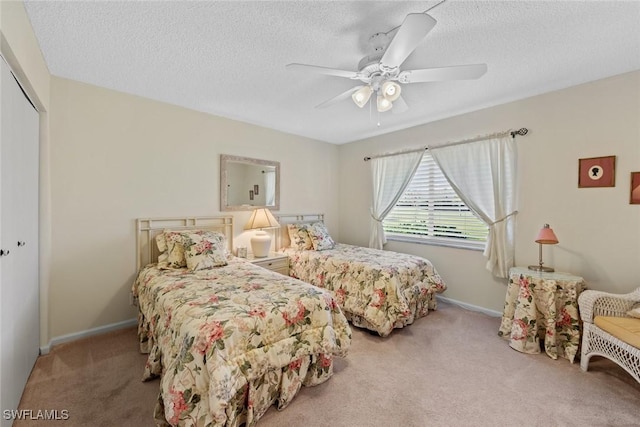 bedroom featuring a textured ceiling, ceiling fan, light carpet, and a closet