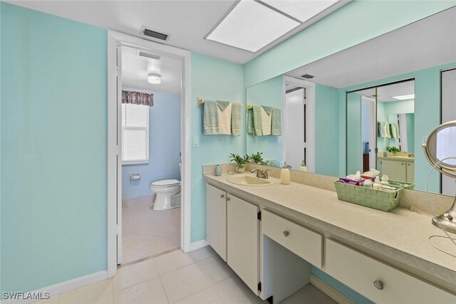 bathroom with toilet, vanity, a skylight, and tile patterned floors