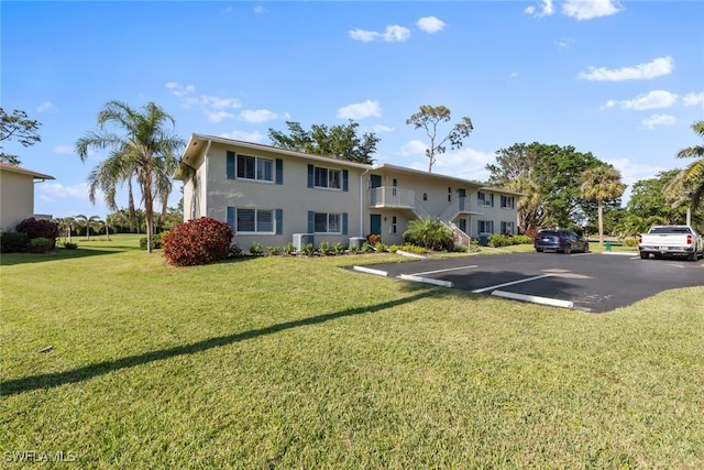 view of front of property with central air condition unit and a front lawn