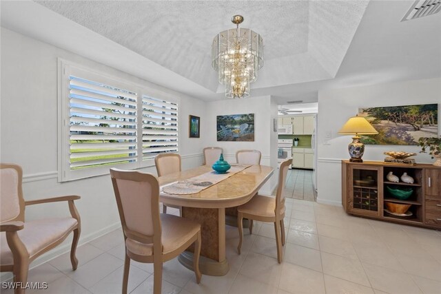 dining space with a raised ceiling, light tile patterned floors, a chandelier, and a textured ceiling