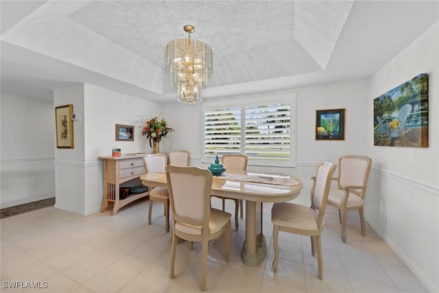 dining space with a tray ceiling and a notable chandelier