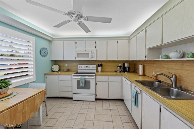 kitchen featuring white appliances, white cabinets, sink, light tile patterned floors, and tasteful backsplash