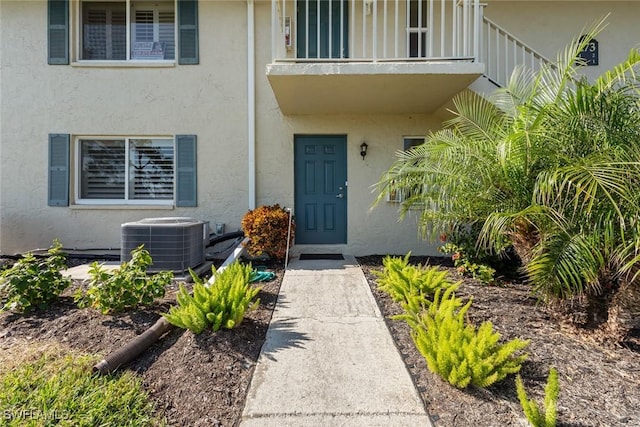 view of exterior entry featuring a balcony and central AC