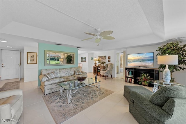 living room with a textured ceiling, a tray ceiling, and ceiling fan