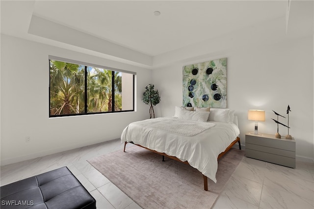 1125 Central Ave Unit 269, Naples, FL 34102 - bedroom featuring light marble finish floors, baseboards, and a tray ceiling