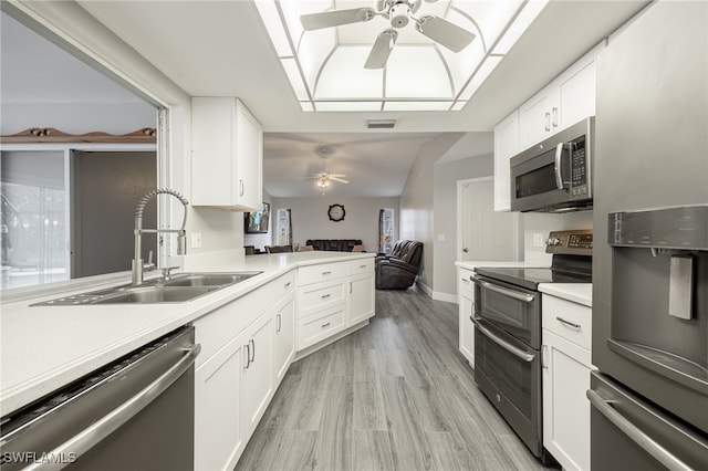 kitchen with white cabinets, sink, appliances with stainless steel finishes, light hardwood / wood-style floors, and kitchen peninsula