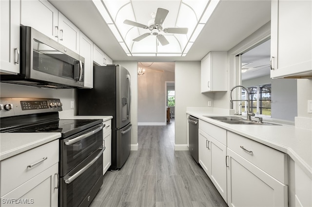 kitchen with a wealth of natural light, white cabinetry, sink, ceiling fan with notable chandelier, and appliances with stainless steel finishes