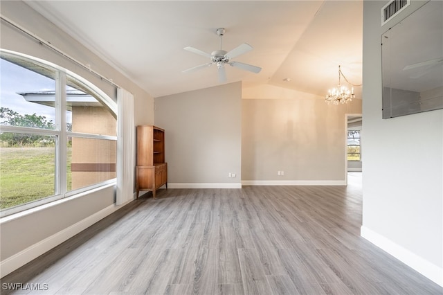 empty room with light hardwood / wood-style flooring, ceiling fan with notable chandelier, and vaulted ceiling