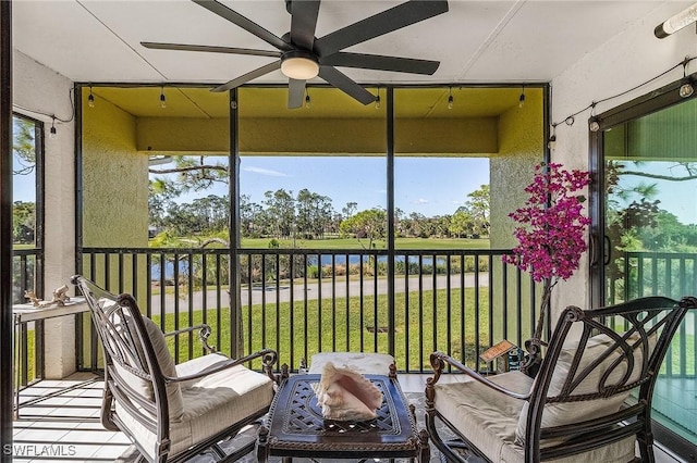 sunroom / solarium with a water view, ceiling fan, and a healthy amount of sunlight