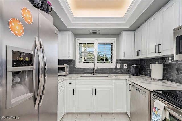 kitchen with light stone countertops, white cabinetry, and appliances with stainless steel finishes