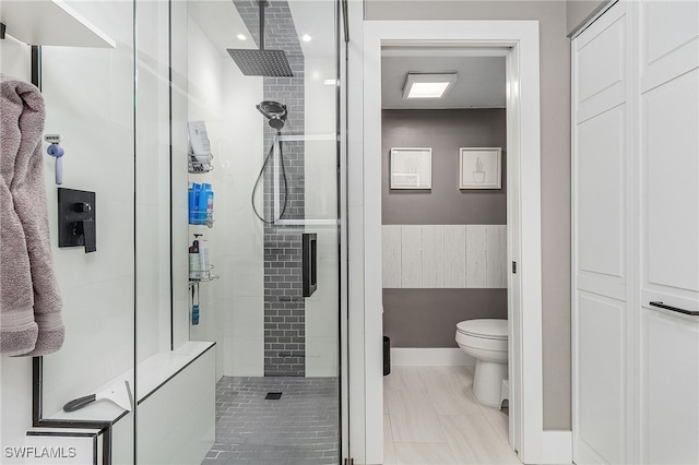 bathroom with tile patterned floors, toilet, and a shower with shower door