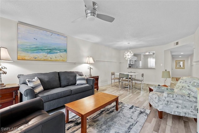 living room with a textured ceiling, light hardwood / wood-style flooring, and ceiling fan with notable chandelier