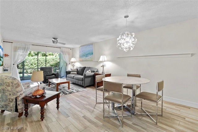 dining space featuring a textured ceiling, light wood-type flooring, and an inviting chandelier