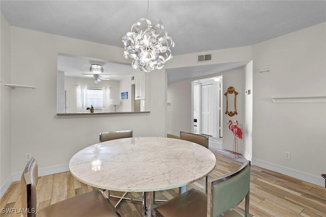 dining room featuring a textured ceiling, light hardwood / wood-style floors, and ceiling fan with notable chandelier