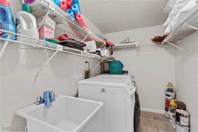 laundry room with sink, light tile patterned floors, washer and dryer, and a textured ceiling