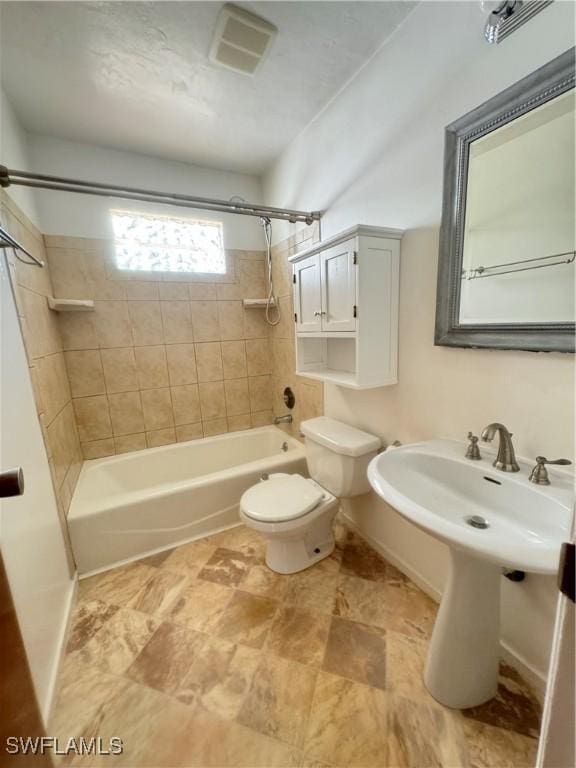 bathroom featuring toilet and tiled shower / bath