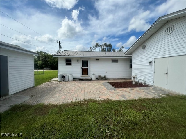 back of house with a lawn and a patio