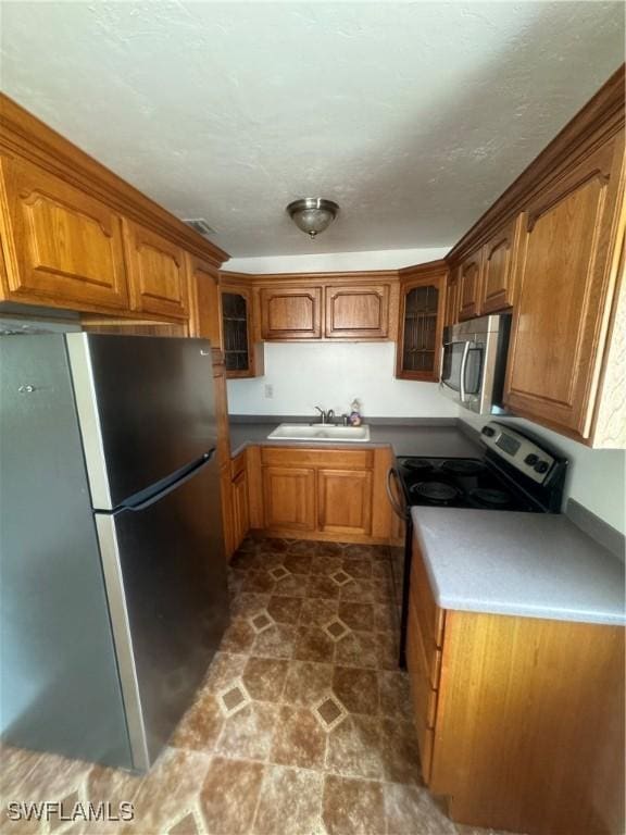 kitchen with a textured ceiling, sink, and appliances with stainless steel finishes