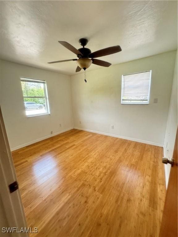 empty room with ceiling fan and light hardwood / wood-style floors